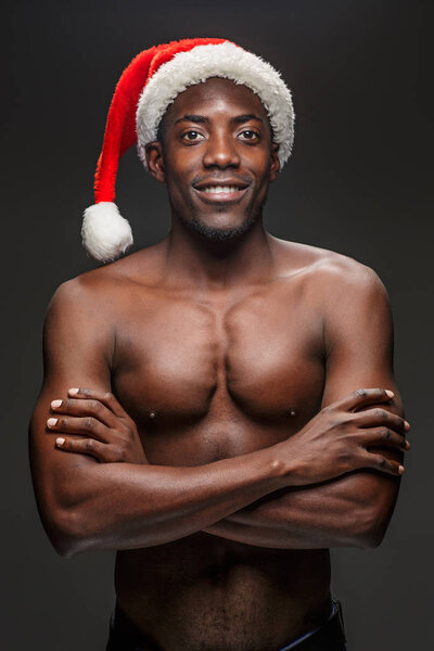 Молодой человек без рубашки в шляпе Санта Клауса
