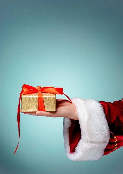 Noel Baba hediye mavi arka plan üzerinde tutan eli — Stok fotoğraf