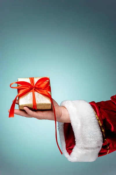 Hand van de Kerstman, bedrijf van een gift op blauwe achtergrond — Stockfoto