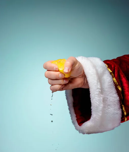 Foto van Santa Claus hand knijpen citroen — Stockfoto