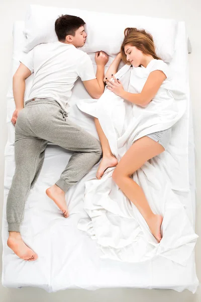 A fiatal kedves házaspár egy ágyban fekve — Stock Fotó