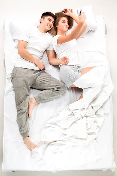La joven pareja adorable acostada en una cama — Foto de Stock