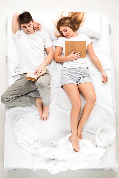 Młoda para piękny, leżąc w łóżku z książek — Zdjęcie stockowe