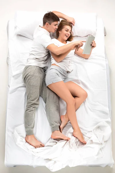 Tânărul cuplu minunat întins într-un pat cu laptop — Fotografie, imagine de stoc