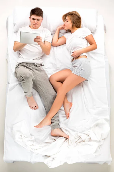 Het jonge mooie paar liggen in een bed met laptop — Stockfoto