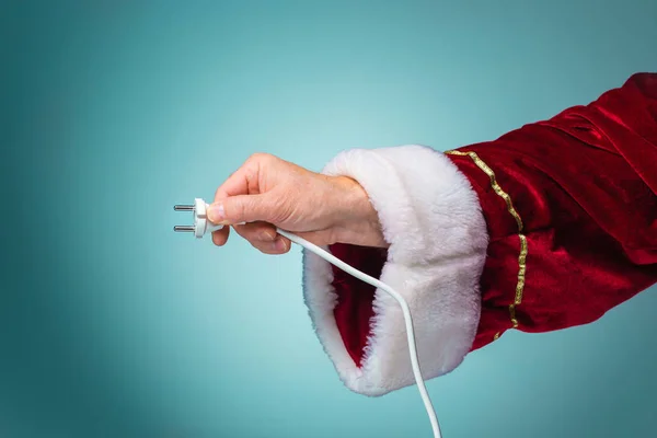 Claus Santa elektrik prizinden mavi arka plan üzerinde tutan el — Stok fotoğraf
