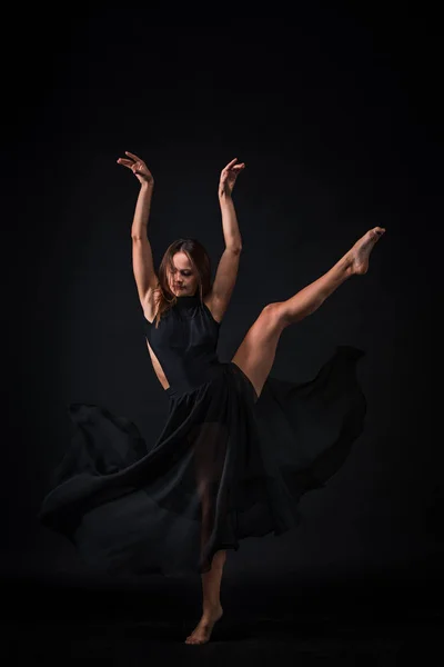 Joven hermosa bailarina en vestido beige bailando sobre fondo negro — Foto de Stock