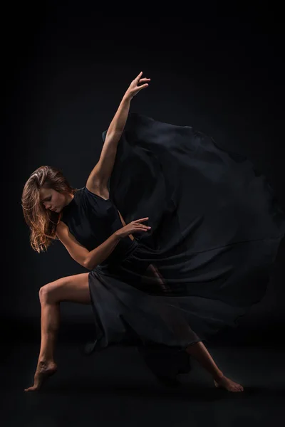Joven hermosa bailarina en vestido beige bailando sobre fondo negro — Foto de Stock