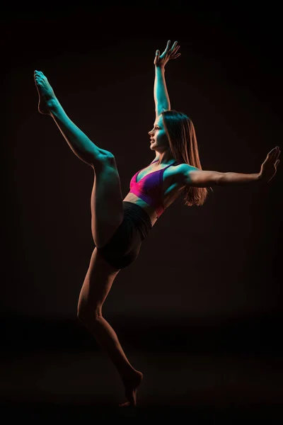 Jonge mooie danseres in beige jurk dansen op zwarte achtergrond — Stockfoto