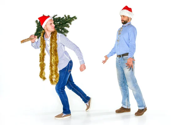 El joven de Santa Gorra llevando un árbol de Navidad — Foto de Stock