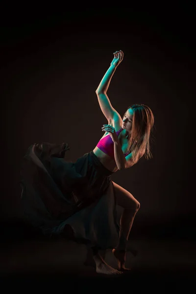 Joven hermosa bailarina en vestido beige bailando sobre fondo negro — Foto de Stock