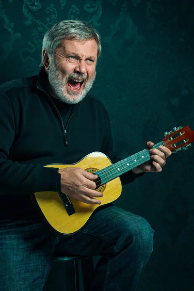 Studioporträt eines älteren Mannes mit Gitarre. — Stockfoto