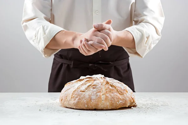 Мужские руки в муке и деревенском органическом буханке хлеба — стоковое фото