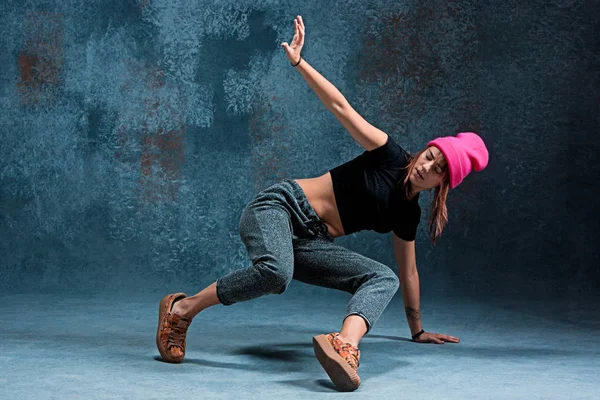 Young girl break dancing on wall background.