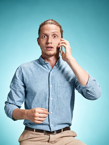 De jonge verraste de Kaukasische mens op blauwe achtergrond — Stockfoto