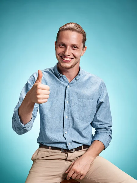 Щасливий збуджуючий молодий чоловік посміхається на синьому фоні — стокове фото