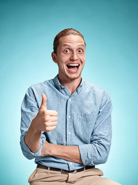 Happy vzrušují mladý muž s úsměvem nad modrým pozadím — Stock fotografie