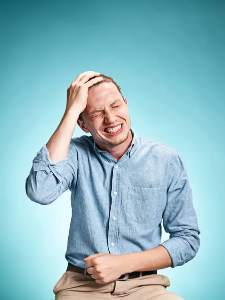 The disappointed young man over blue background — Stock Photo, Image