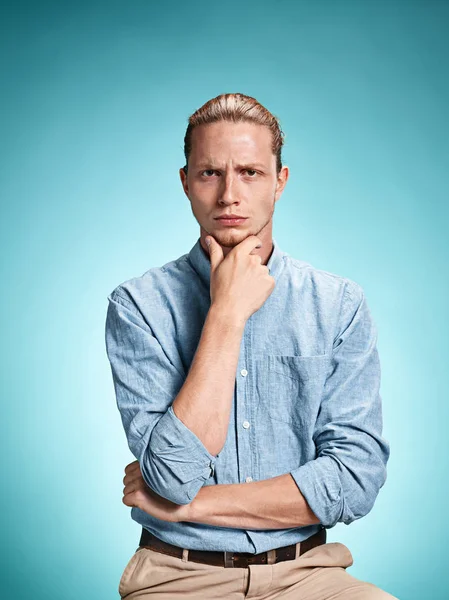 The serious young man over blue background — Stock Photo, Image