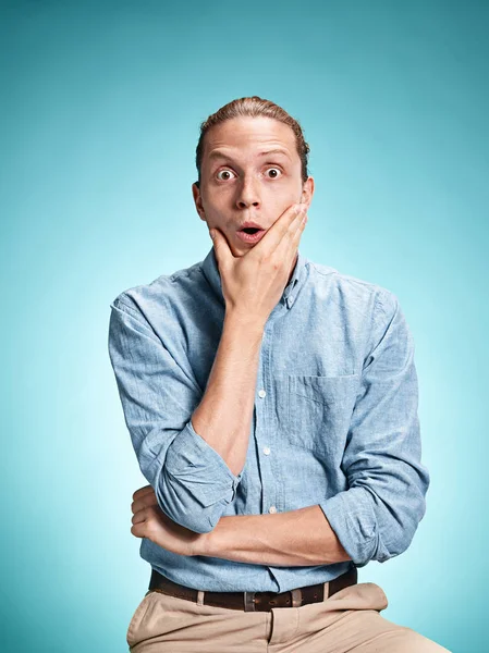 El joven sorprendido sobre fondo azul — Foto de Stock