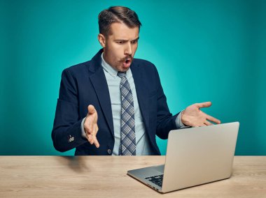 Üzgün genç adam masada dizüstü bilgisayarda çalışma