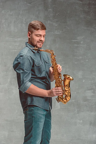 Gelukkig saxofonist met sax over grijze achtergrond — Stockfoto