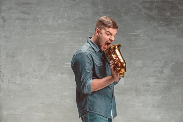 Happy saxofonista s sax nad šedým pozadím — Stock fotografie