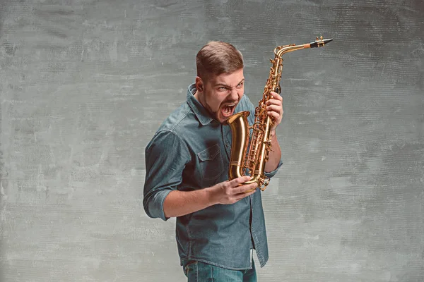 Happy saxofonista s sax nad šedým pozadím — Stock fotografie