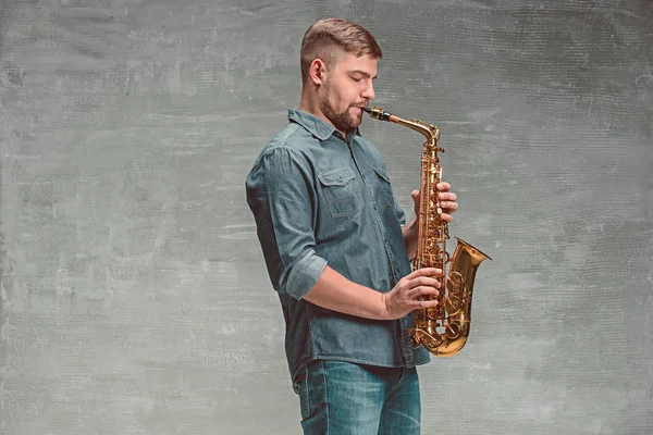 Saxofonista feliz tocando música no sax sobre fundo cinza — Fotografia de Stock