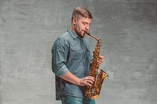 Feliz saxofonista tocando música en saxo sobre fondo gris — Foto de Stock