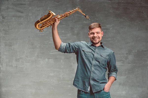 Saxofonista feliz con saxofón sobre fondo gris — Foto de Stock