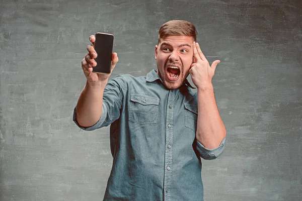 O jovem homem de negócios caucasiano sorridente em fundo cinza com telefone — Fotografia de Stock