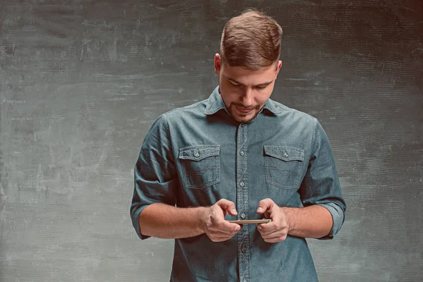 El joven sonriente hombre de negocios caucásico sobre fondo gris con teléfono — Foto de Stock