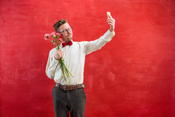 Joven hombre hermoso con flores y teléfono — Foto de Stock