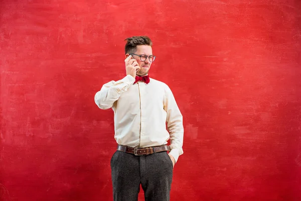 Retrato del hombre desconcertado hablando por teléfono un fondo rojo — Foto de Stock