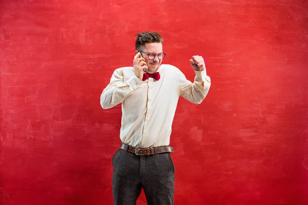 Porträt eines verwirrten Mannes, der am Telefon einen roten Hintergrund spricht — Stockfoto