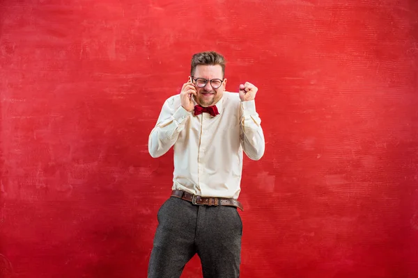 Porträt eines verwirrten Mannes, der am Telefon einen roten Hintergrund spricht — Stockfoto