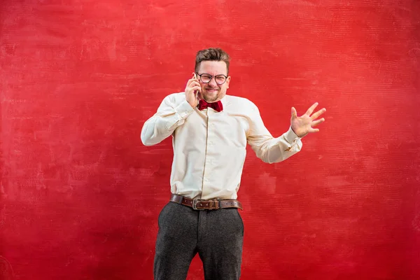 Retrato del hombre desconcertado hablando por teléfono un fondo rojo — Foto de Stock