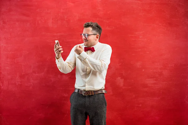 Portrait of puzzled man talking by phone a red background — Stock Photo, Image