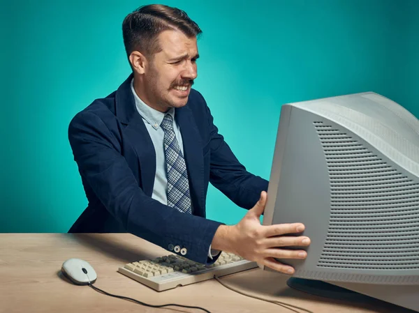 Homem de negócios irritado usando um monitor contra fundo azul — Fotografia de Stock