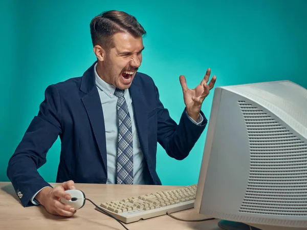 Wütender Geschäftsmann mit Monitor vor blauem Hintergrund — Stockfoto