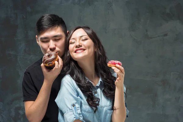 Jeune couple asiatique profiter de manger de doux beignet coloré — Photo