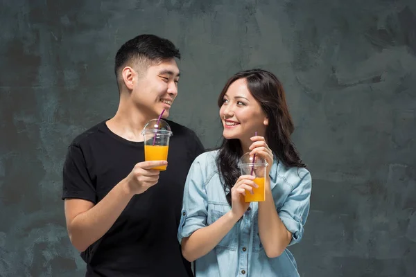 若いです可愛いですアジアのカップルオレンジジュースのグラス — ストック写真