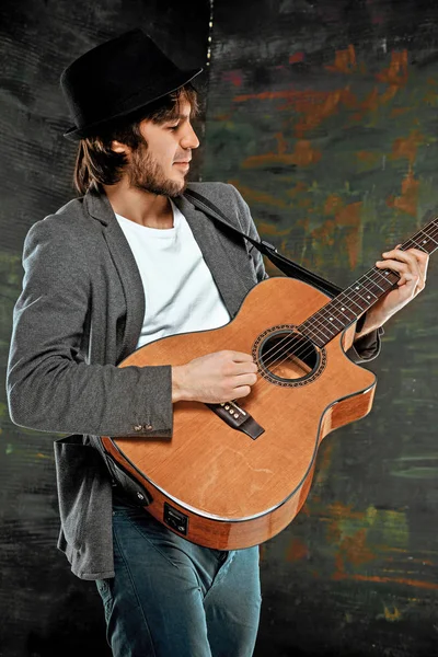 Tipo fresco con sombrero tocando la guitarra sobre fondo gris — Foto de Stock