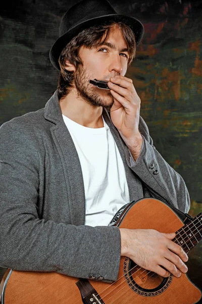 Tipo fresco con sombrero tocando la guitarra sobre fondo gris — Foto de Stock