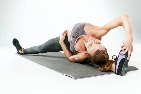 Mooie slanke brunette doen sommige stretching oefeningen in een sportschool — Stockfoto