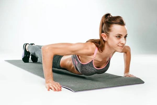 Belle brune mince faisant quelques pompes a la salle de gym — Photo