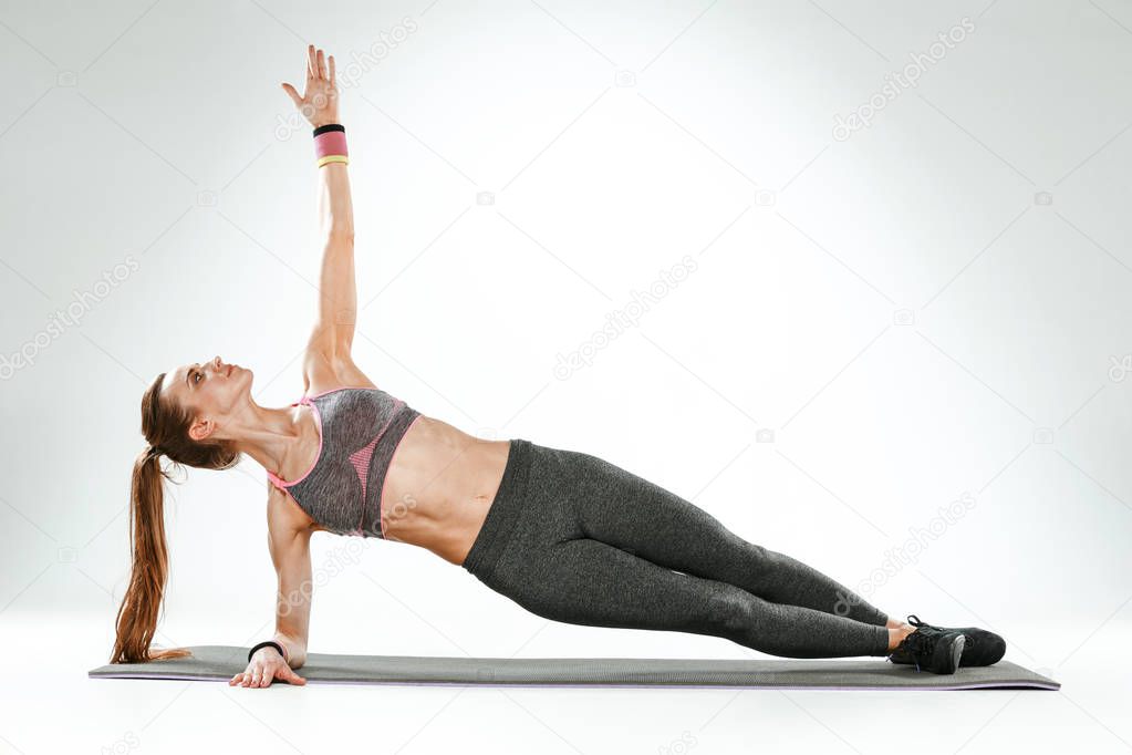 Beautiful slim brunette doing some stretching exercises in a gym
