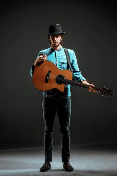 Cool guy standing with guitar on dark background — Stock Photo, Image