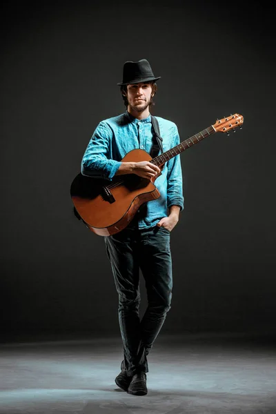 Cool guy standing with guitar on dark background — Stock Photo, Image